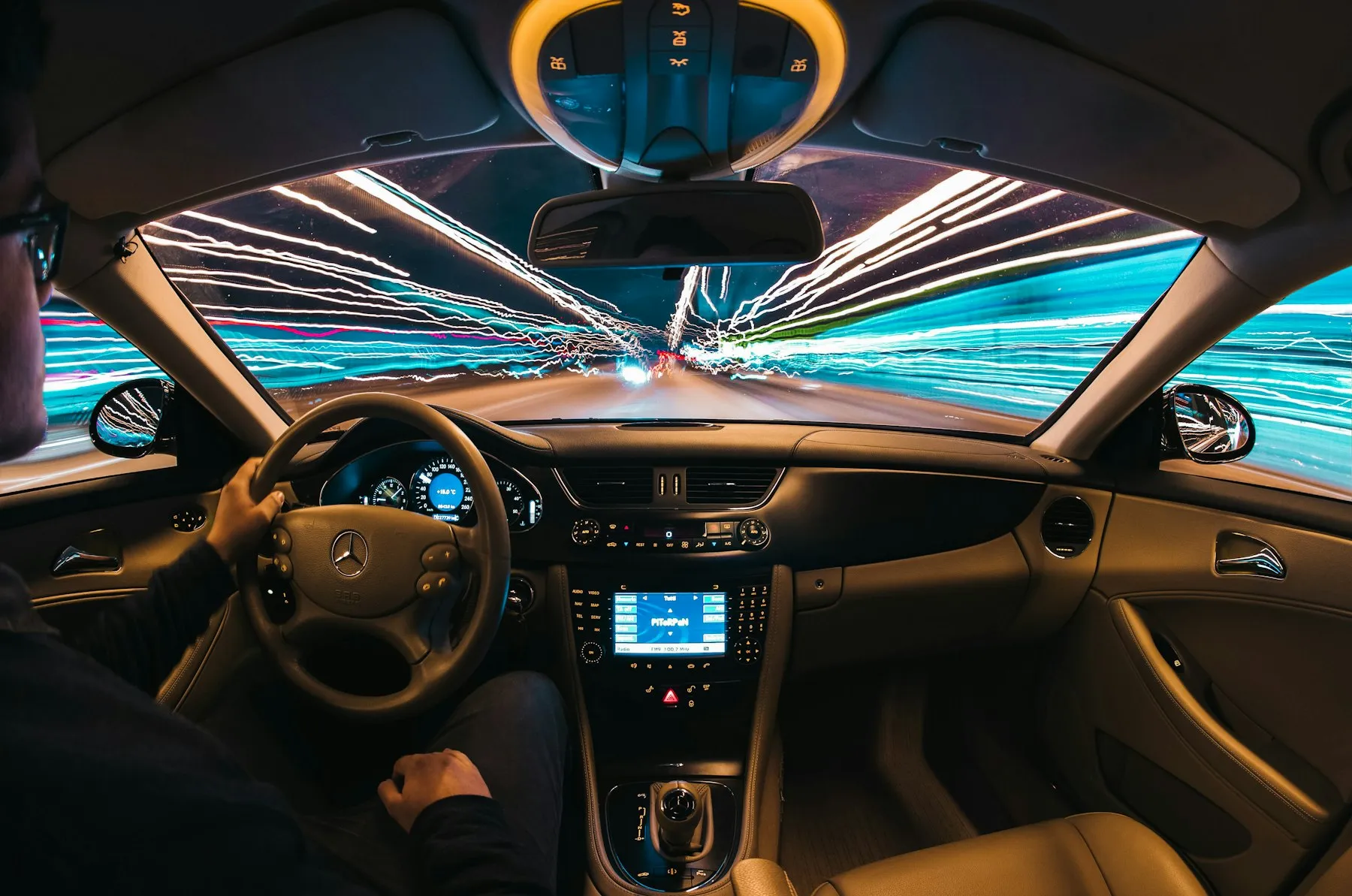 Habitacle d'une berline avec des traînées lumineuses sur la route